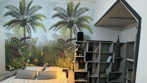 A bedroom with a bed, a bookshelf, and a mural of tropical plants. - 4 bedroom house with garden near Lille  (Tourcoing)