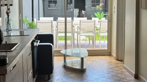 A modern kitchen with a built-in stove, a glass dining table, and a sliding glass door leading to an outdoor patio with a garden and a shed. - 4 bedroom house with garden near Lille  (Tourcoing)