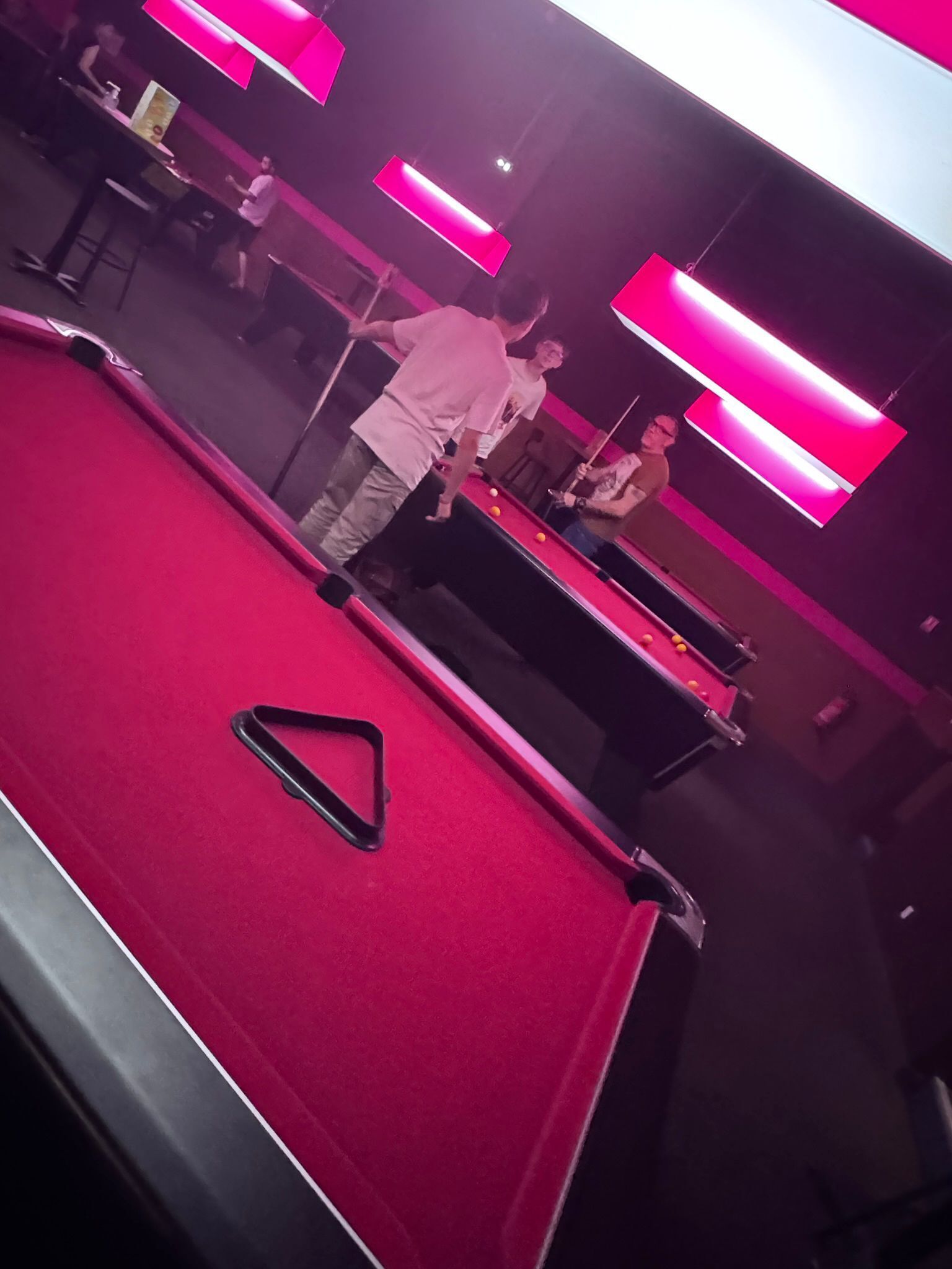 A pool table with a red felt surface and a triangular cue ball.