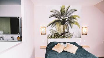 A bedroom with a bed, a nightstand, a mirror, and a wall-mounted light fixture.