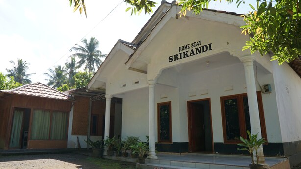 Un edificio de dos pisos con un letrero que dice 'HOME STAY SRIKANDI'.