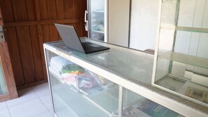 Una computadora portátil sobre una barra de vidrio, con un muro de madera y un muro con baldosas al fondo.