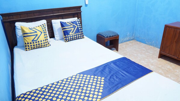 A bed with a blue and yellow polka dot bedspread, two pillows with similar patterns, and a wooden headboard. - Hotel O Homestay Srikandi Pulau Merah BeachNearPantai Pancer (Sumberagung)