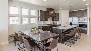 A modern kitchen with a large island, dark wood cabinets, and stainless steel appliances.