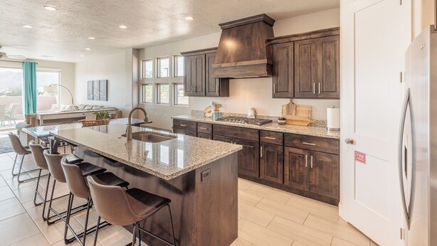 A spacious kitchen with dark wood cabinets, a granite countertop, and a large island with bar stools.