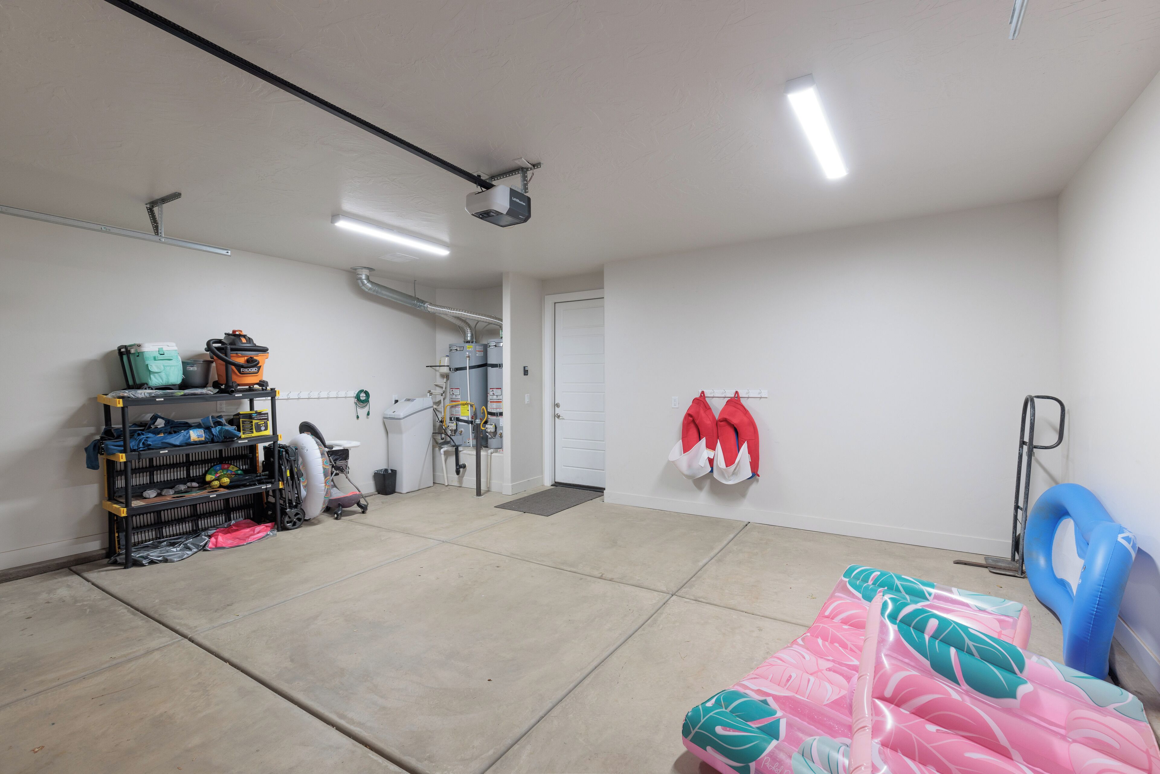 A clean, well-lit garage with a workbench, a water filtration system, and a storage shelf.
