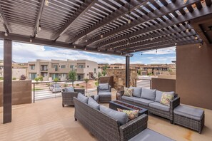 Relax in a cozy outdoor space with wicker sofas and chairs, sheltered by a pergola and string lights.