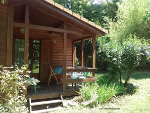 Eine Holzhütte mit Veranda, Tisch und Stühlen.