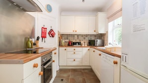 A modern kitchen with white cabinets, a stainless steel range hood, a microwave, and a dishwasher.