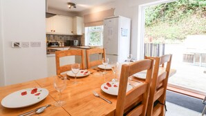 A dining area with a wooden table set for four, white plates, and wine glasses.