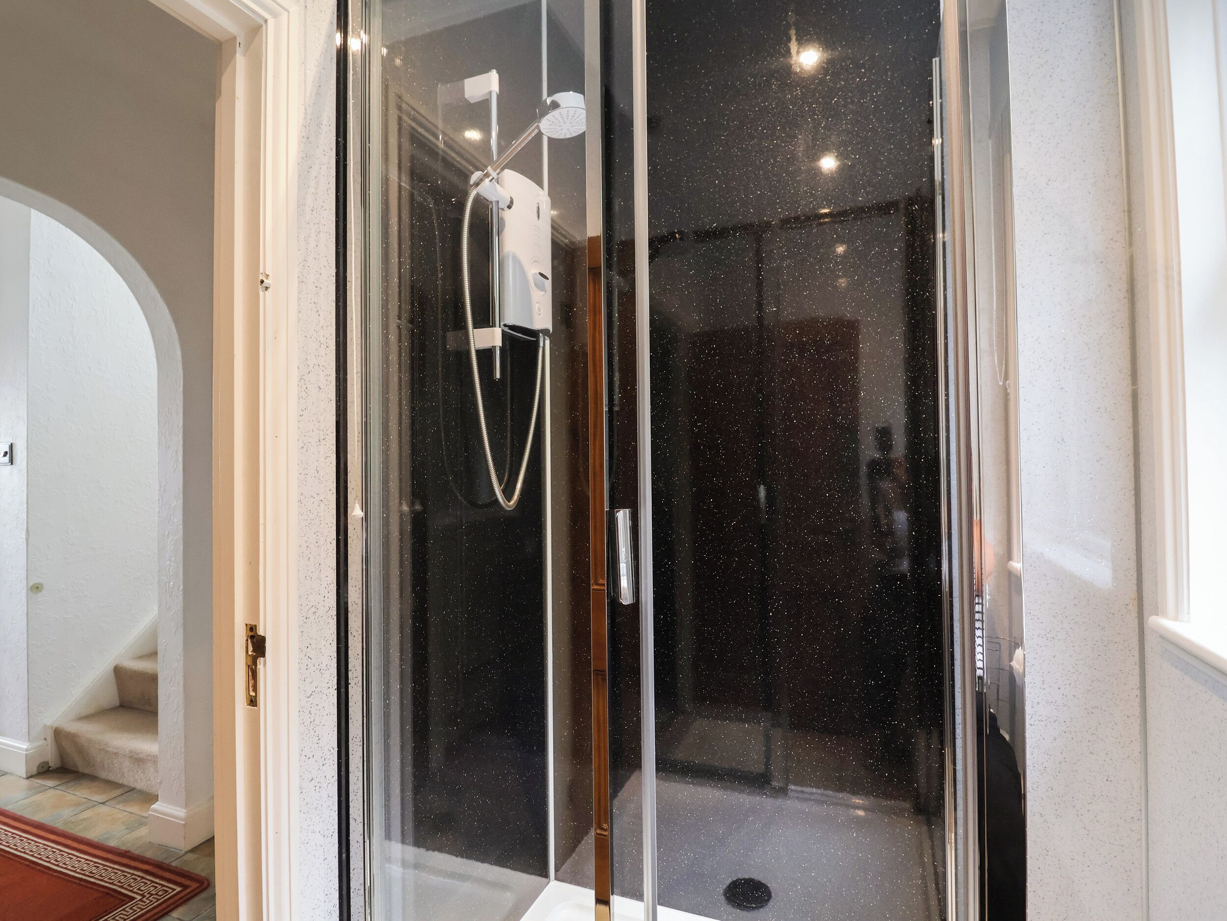 A glass-enclosed shower area with a handheld showerhead and a handheld shower attachment.
