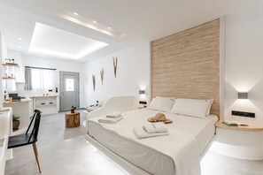Un dormitorio moderno con una cama grande, mesitas de noche, un escritorio y un baño al fondo.
