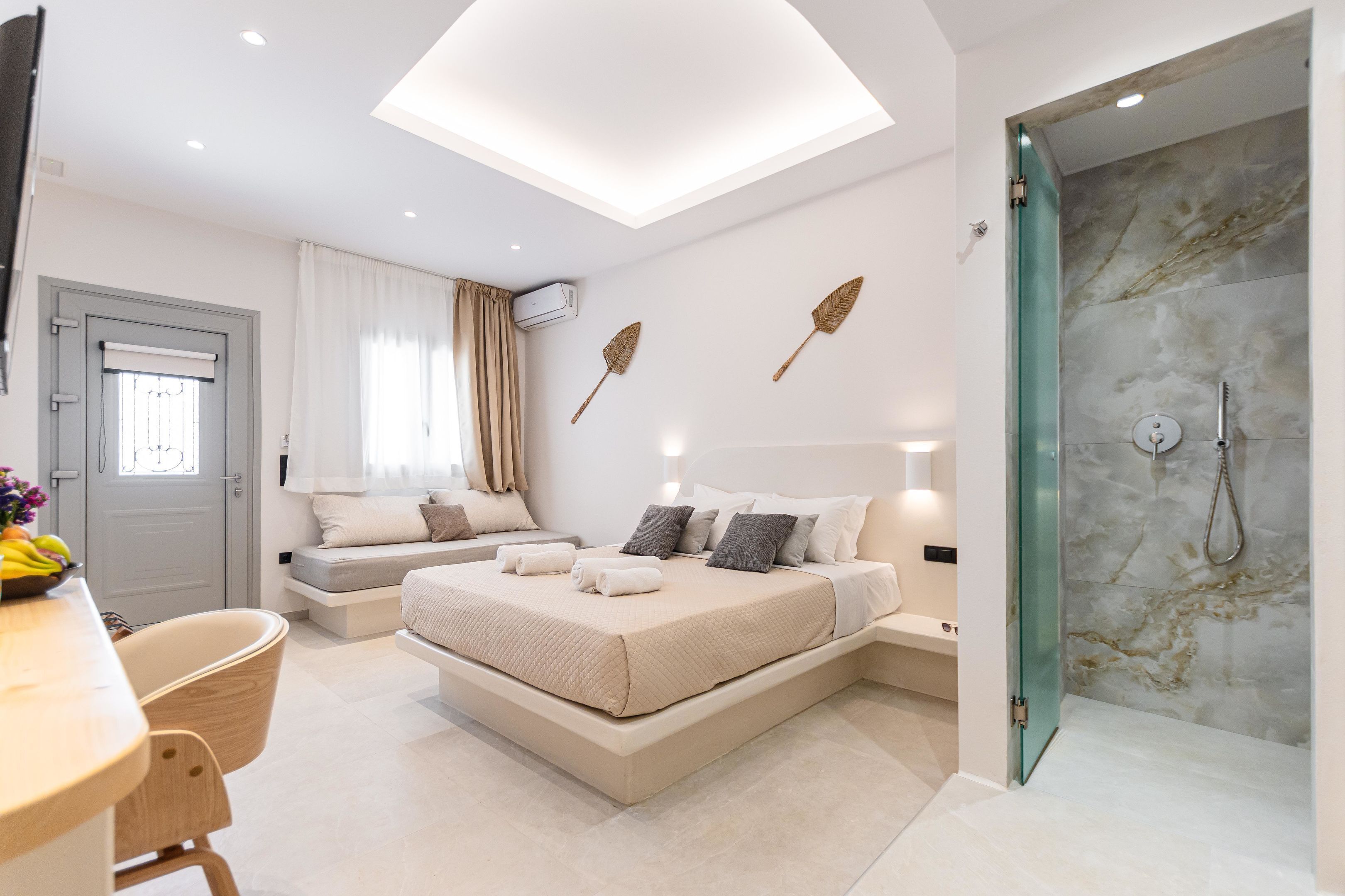 Quarto moderno com cama grande, escrivaninha e área de chuveiro.
