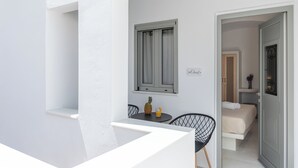 A balcony with a table, chairs, a pineapple, and a glass of orange juice. - Adama's Suites Naxos (Naxos)