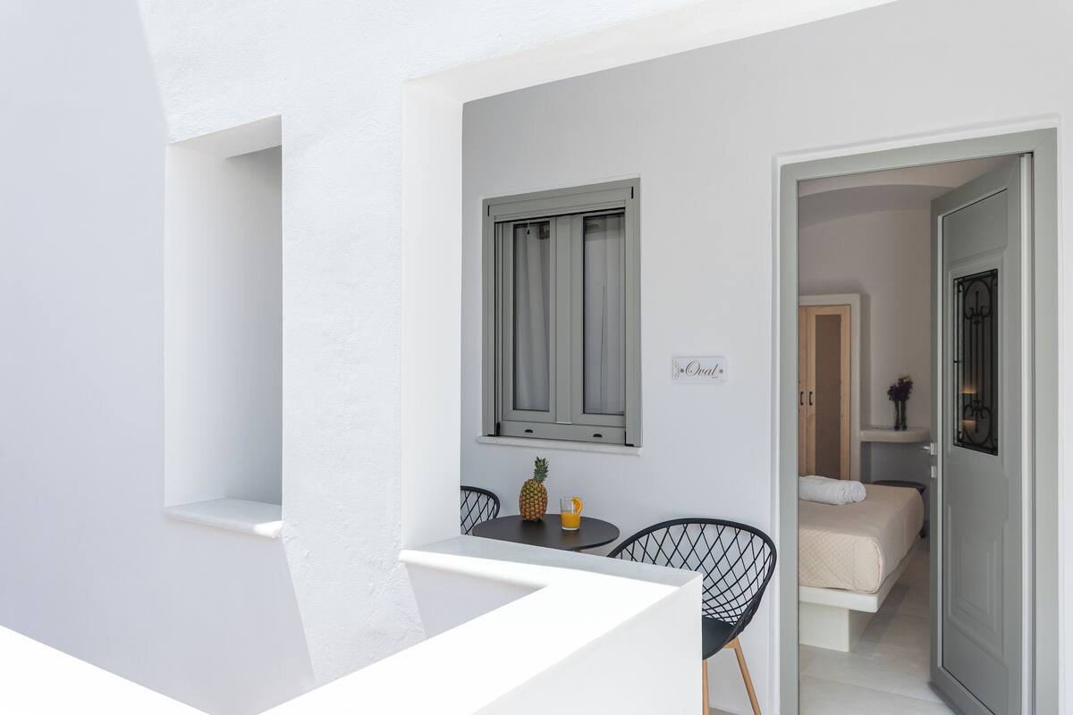 A balcony with a table, chairs, a pineapple, and a glass of orange juice.