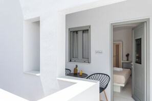 A balcony with a table, chairs, a pineapple, and a glass of orange juice.