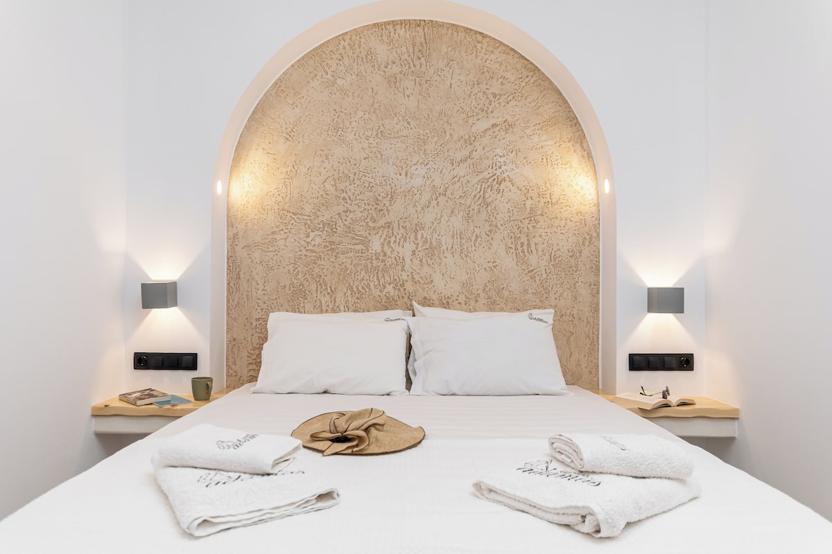 A modern hotel room with a large bed, two bedside tables, and a unique textured headboard.