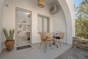 Un patio con sillas de mimbre, una mesa y una planta en maceta.