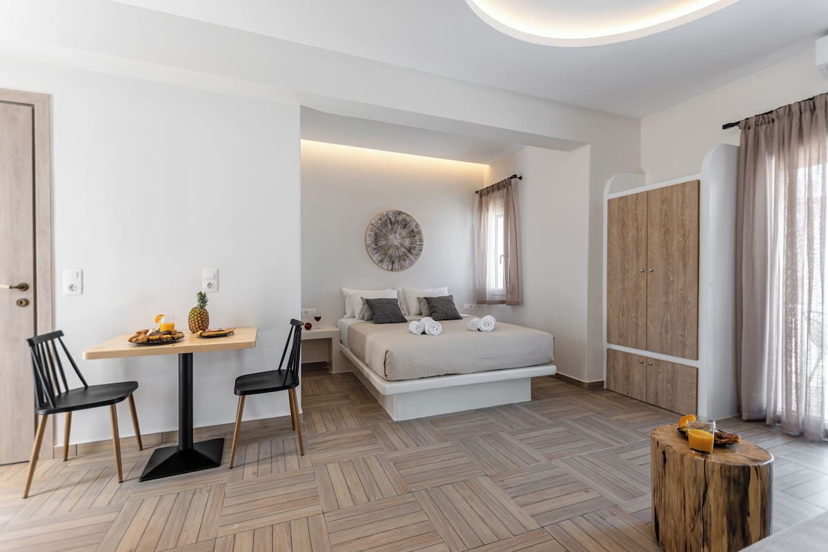 A bedroom with a bed, bedside table, and a dining area with chairs.