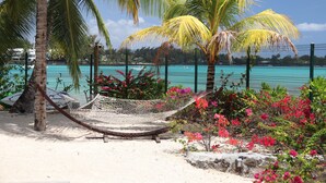 A hammock on a sandy beach with a turquoise pool and palm trees in the background. - Pointe d'Azur by Horizon Holidays (Grand-Baie)