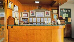 Un comptoir d’accueil orné de cadres contenant des certificats, une horloge et une machine à café.