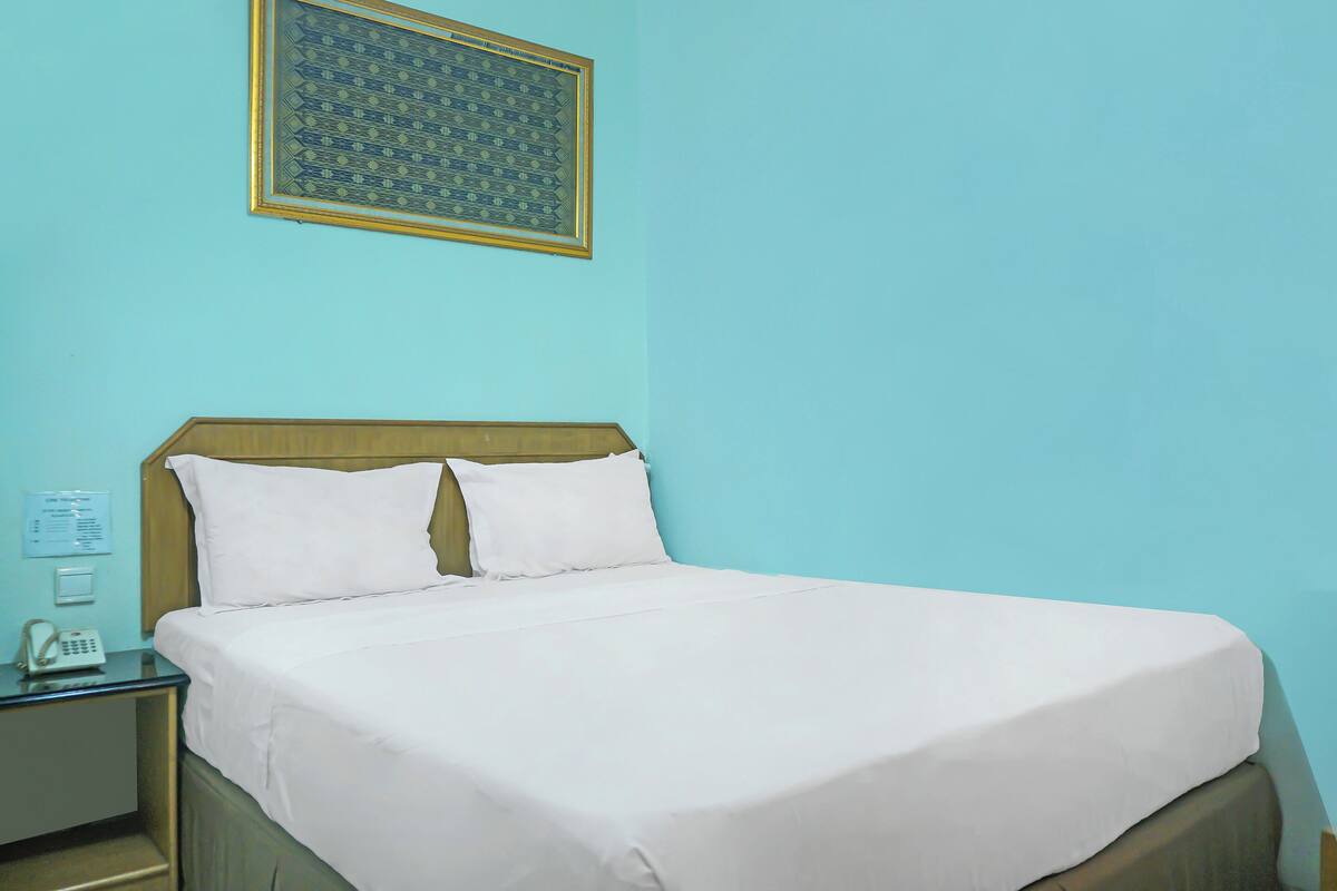 Cama bem arrumada com lençóis brancos em quarto com paredes azul claro.