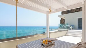 Un balcon avec vue sur la mer, une table à manger où le petit-déjeuner est servi, et un intérieur moderne.