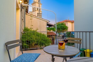 A balcony with a round table, two chairs, and a glass of red wine. - Casa Tonia (Premantura)