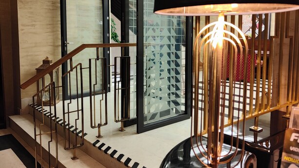 A modern staircase with a black railing, a black lamp, and a glass elevator door. - Hotel Hutnik (Stalowa Wola)