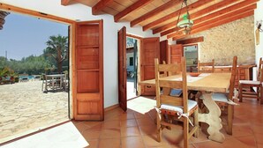 A spacious room with a large wooden dining table, chairs, and a view of the beach. - Villa Martorell, 3 bedroom villa near crystalline beaches of Cala Sant Vicenç (Pollença)