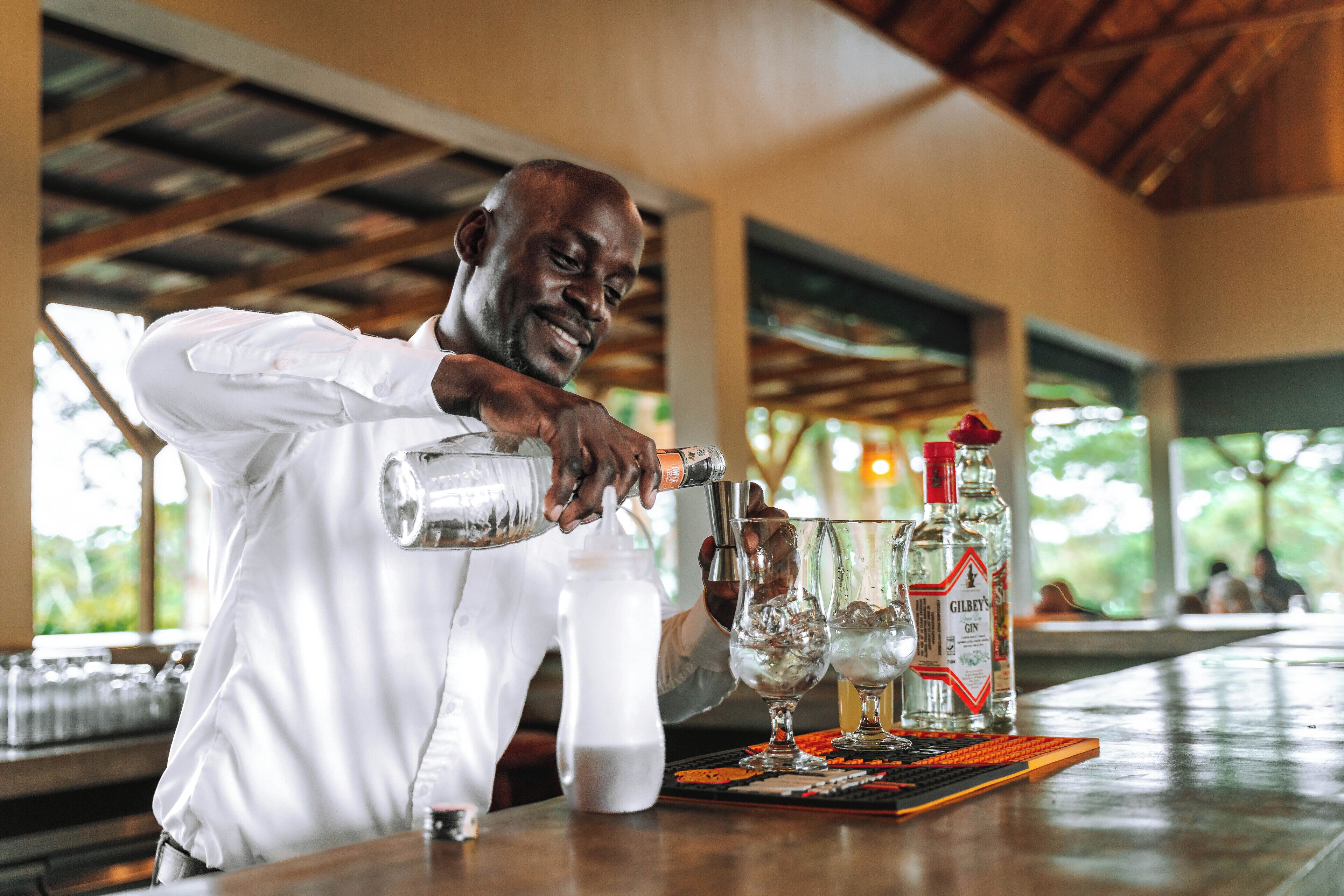 A bartender pouring a drink into a glass.