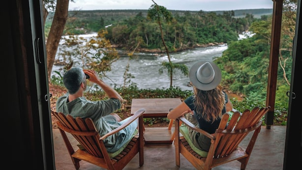 Two people seated at a table with a view of a river and forest.