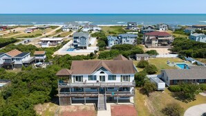 A coastal residential area with houses, a beach, and a clear view of the ocean. - Bohemian Breeze: Oceanside | Pool and Hot Tub (Southern Shores)