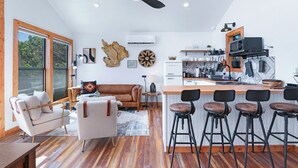Eine moderne Küche mit einer zentralen Kochinsel, Barhocker und einer Essecke mit Sofa und Couchtisch.