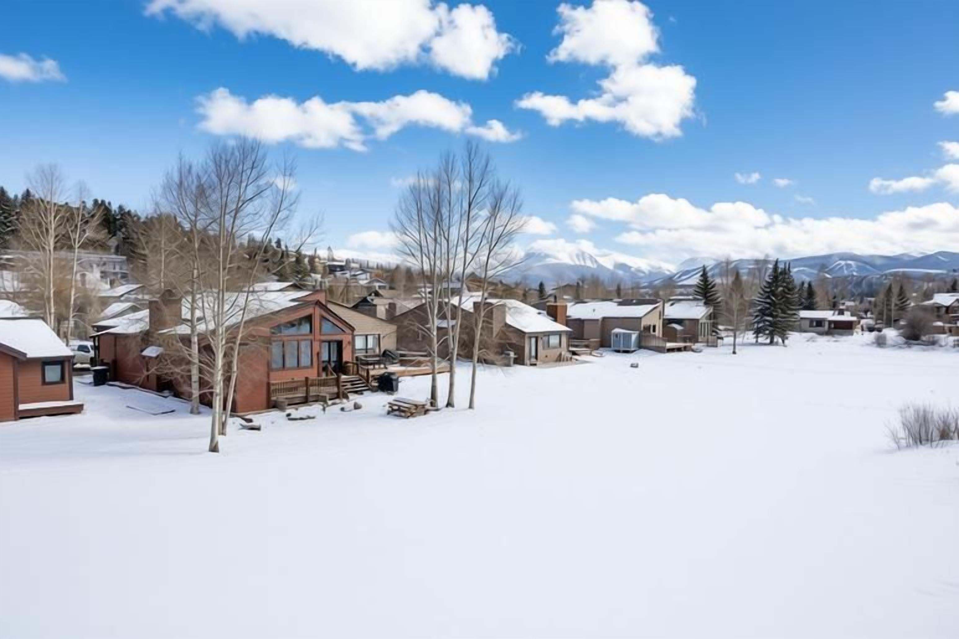 A residential area with houses, a clear sky, and snow-covered ground.
