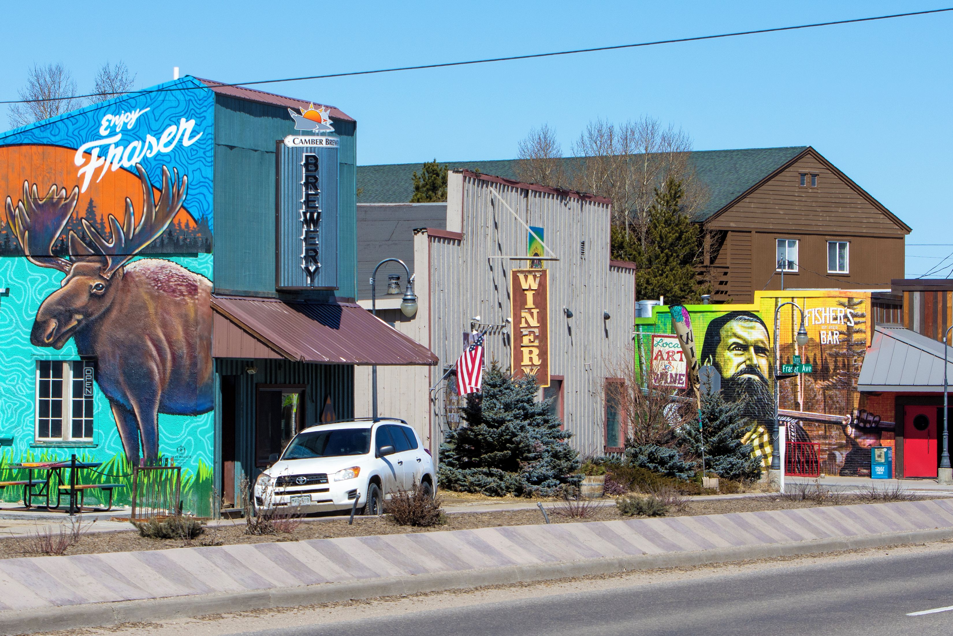 Un edificio con un murale raffigurante un alce, una insegna per 'Camber Brewery' e una insegna con scritto 'Fisher's Bar'.