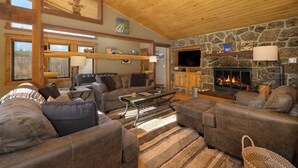 A cozy living room with leather sofas, a stone fireplace, and a wooden ceiling. - 701B Quail Family & pet friendly 3 bedroom rental private hot tub (Fraser)