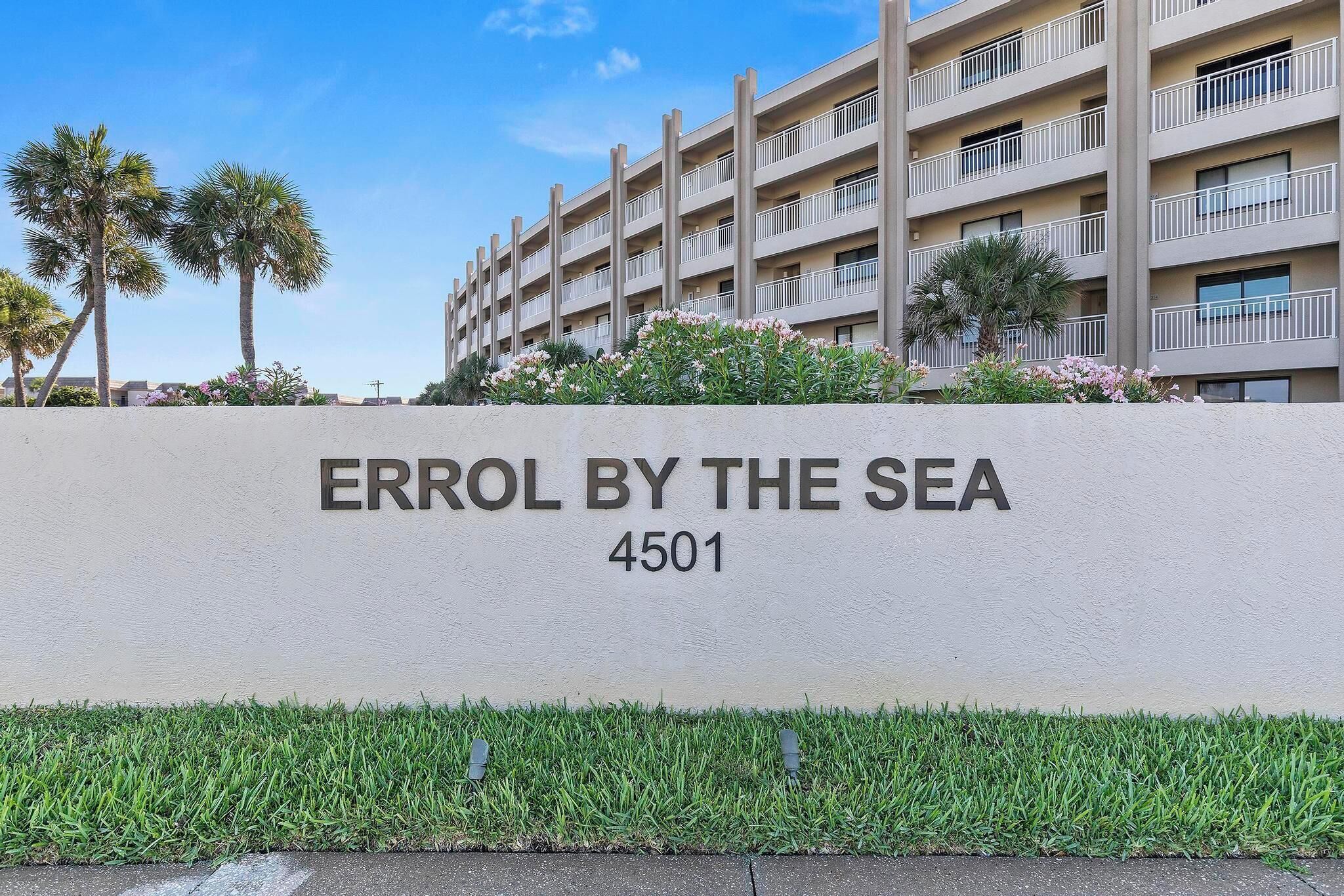 Un edificio con el letrero "ERROL BY THE SEA 4501" y un césped bien cuidado con hierba y plantas pequeñas.
