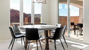 A modern dining area with a round table, black chairs, and a chandelier.