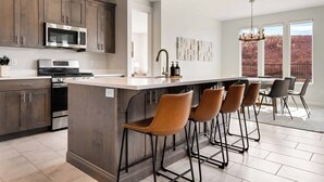 A modern kitchen with dark wood cabinets, stainless steel appliances, and a central island with bar stools.