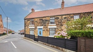 A stone house with a tiled roof, a blue door, and a black fence. - Host & Stay | Stone Row (Saltburn-by-the-Sea)