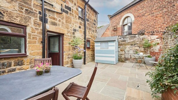 A stone and brick building with a patio area, a small shed, and a table with chairs. - Host & Stay | Stone Row (Saltburn-by-the-Sea)