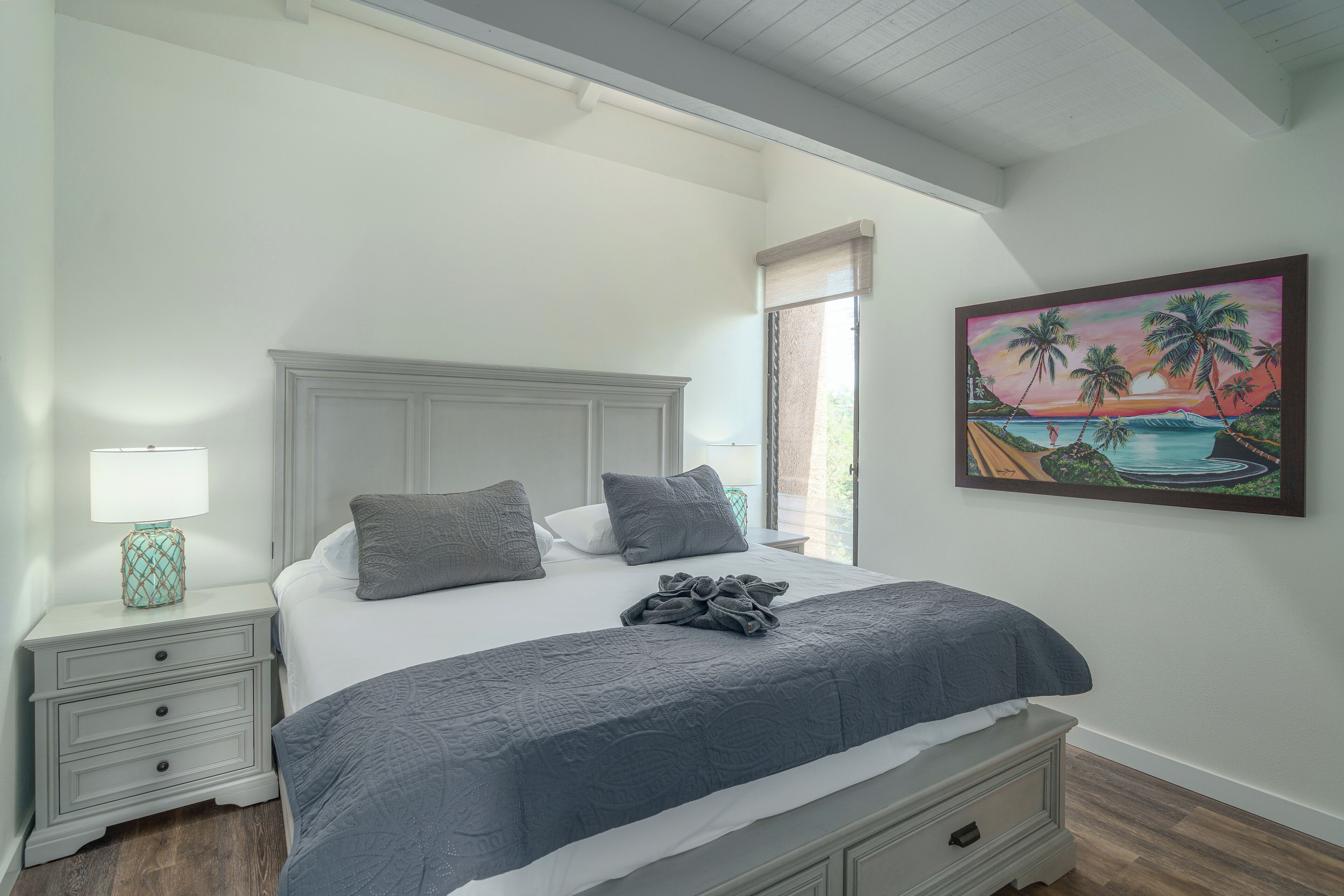 A bedroom with a bed, nightstands, a painting, and a window.