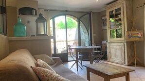 A cozy living room with a sofa, a wooden table, and a dining area with chairs. - Appartement Proche de la Plage (Cavalaire-sur-Mer)