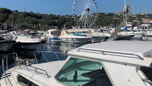 A marina with several boats docked, a Ferris wheel in the background, and a clear blue sky. - Appartement Proche de la Plage (Cavalaire-sur-Mer)