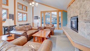 A spacious living room with leather sofas, a wooden coffee table, and a stone fireplace. - Updated 1st Floor End Unit Near Main Street (Frisco)