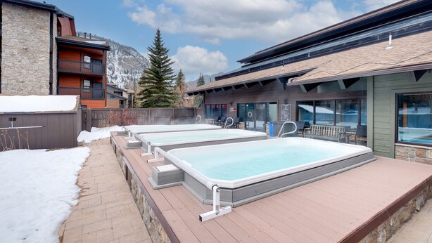 An outdoor swimming pool area with multiple pools, stone walls, and a view of mountains. - Updated 1st Floor End Unit Near Main Street (Frisco)