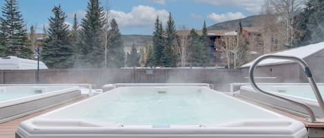 Relax in a hot tub surrounded by evergreen trees and mountain views.