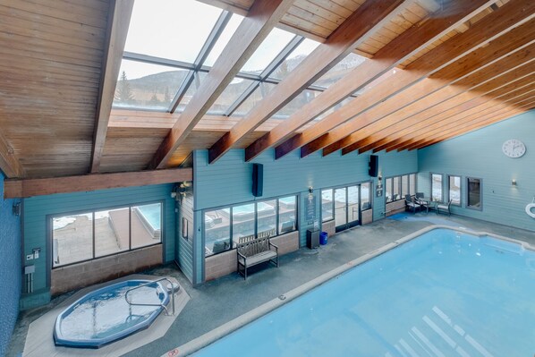 An indoor swimming pool with a wooden ceiling and large windows.