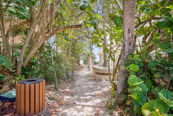 A pathway lined with trees and a wooden trash bin.